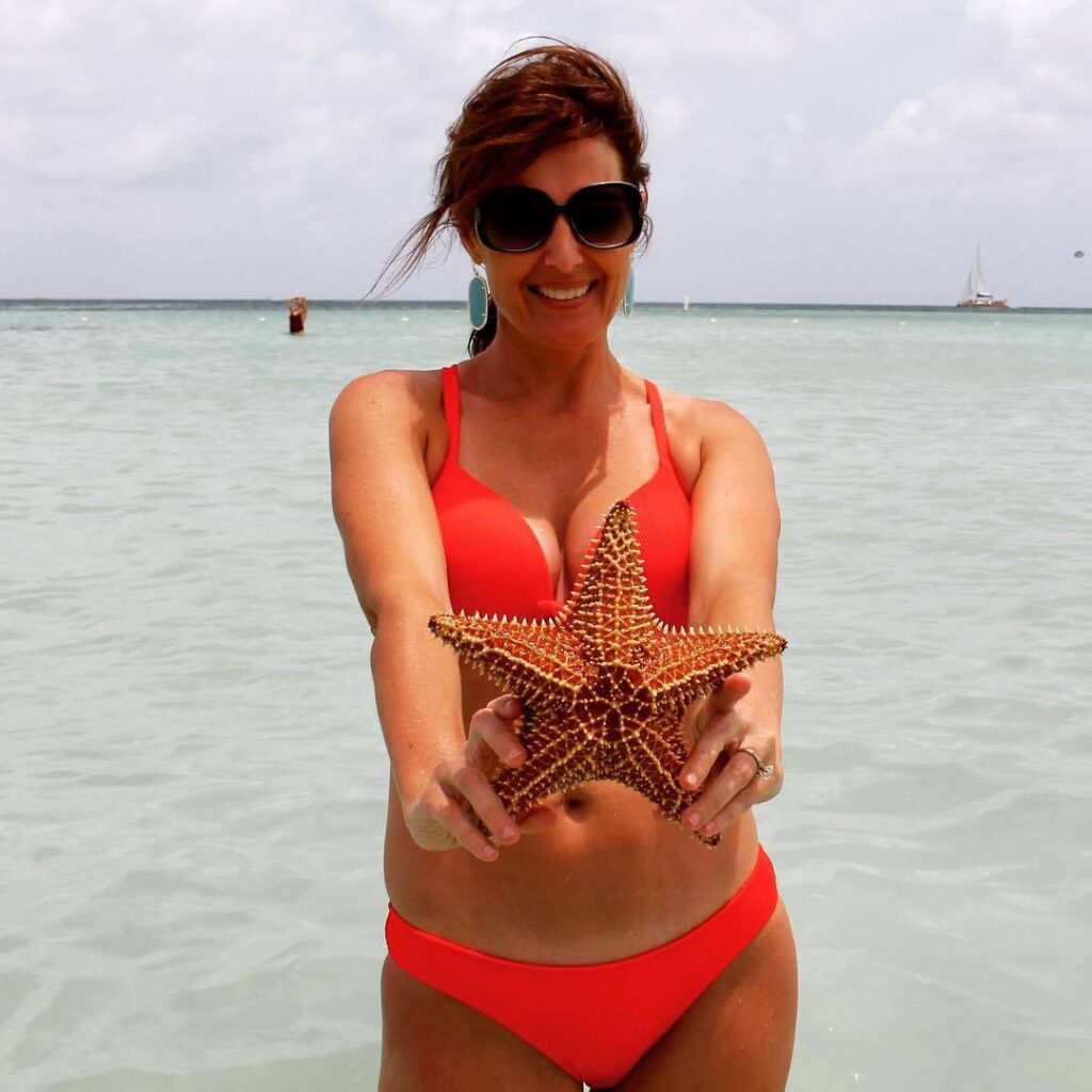 Sheri on the beach with holding a starfish
