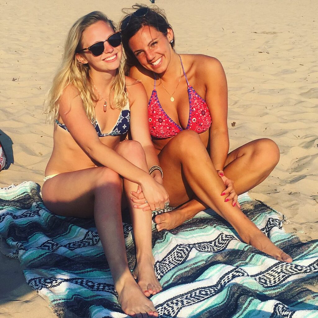 Annie Agar in bikini sat down with her friend on the beach